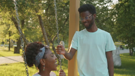 African-American-Woman-Swinging-on-Swing-and-Chatting-with-Boyfriend-in-Park